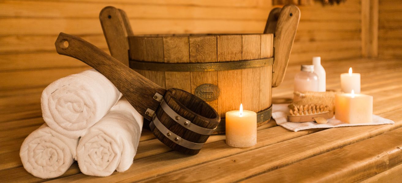 Wnętrze tradycyjnej sauny z drewnianymi ławkami, cebrzykiem i chochlą – sauna sucha i sucho-parowa